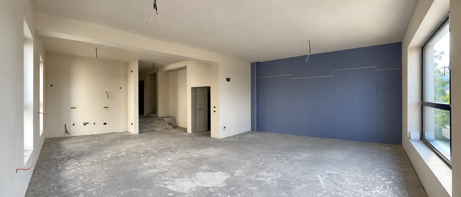 Camera de zi la stadiul de predare, cu pereții gletuiți și peretele dintre unități placat.
